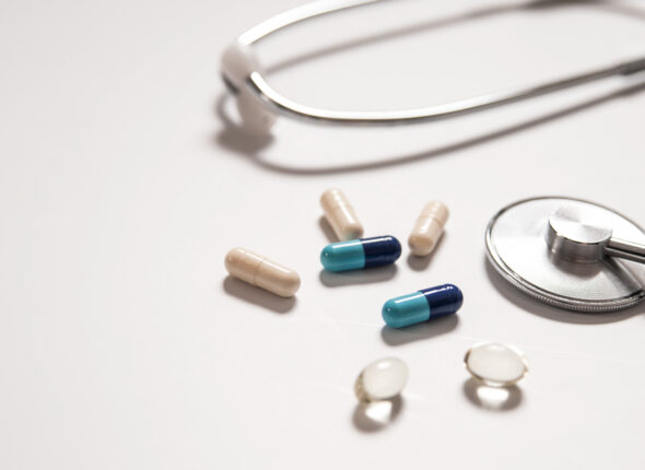 stethoscope on white background with mix pills isolated