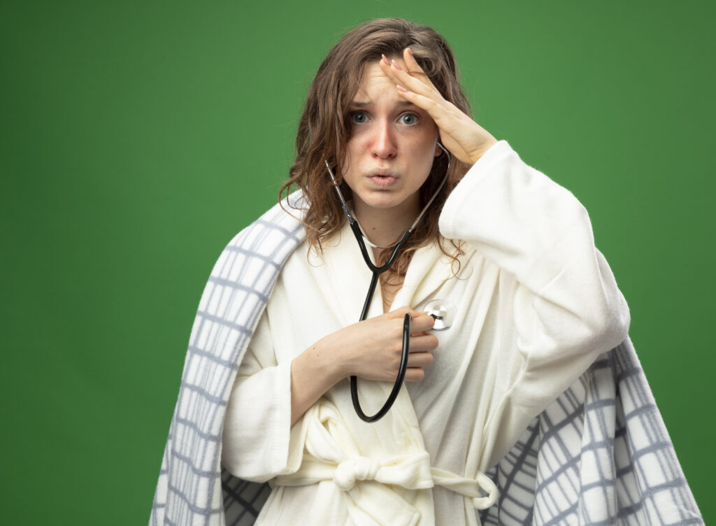 scared-young-ill-girl-wearing-white-robe-wrapped-plaid-listening-her-own-heartbeat-putting-hand-forehead-isolated-green
