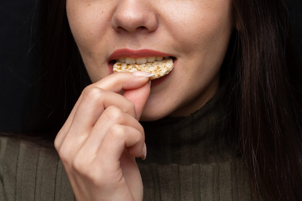 Closeup of a woman biting a cracker under the lights