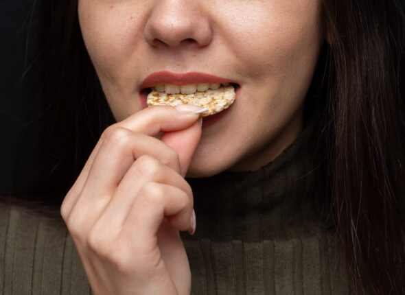 Closeup of a woman biting a cracker under the lights