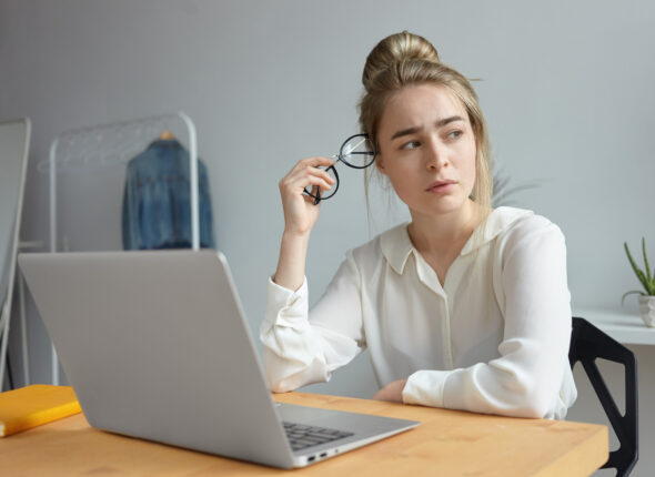 Frustrated exhausted young woman blogger dressed in white blouse