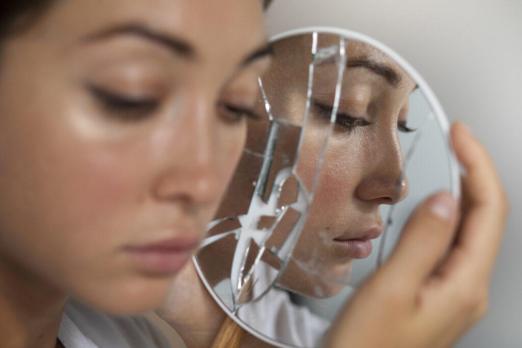 portrait-young-woman-with-low-self-esteem-looking-hand-held-mirror
