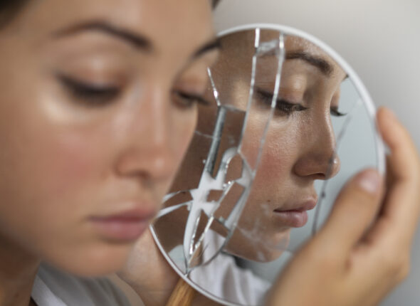 portrait-young-woman-with-low-self-esteem-looking-hand-held-mirror